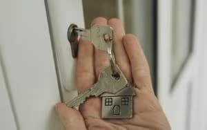 Mão segurando chaves de casa perto da fechadura